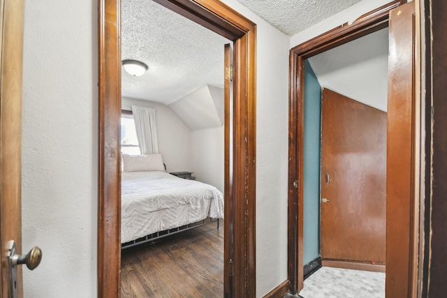 bedroom with a textured ceiling, wood finished floors, and lofted ceiling