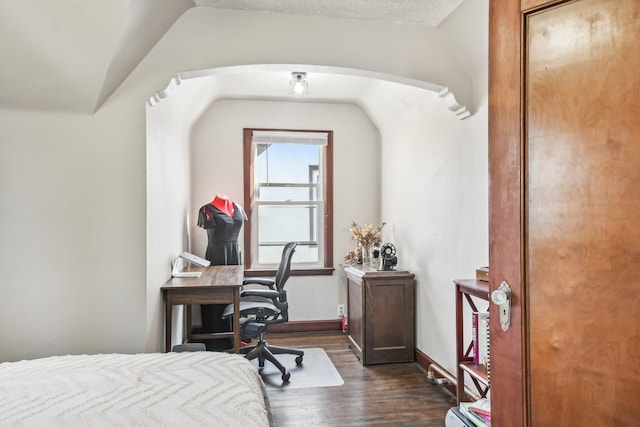 bedroom with dark wood-style flooring, baseboards, arched walkways, and lofted ceiling