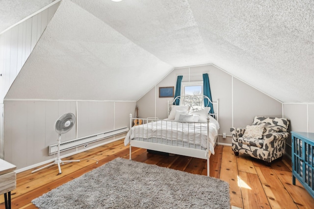 bedroom featuring hardwood / wood-style floors, baseboard heating, a textured ceiling, and lofted ceiling