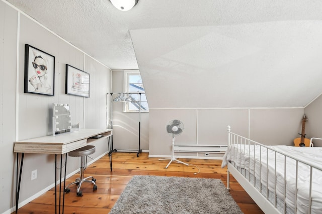 bedroom featuring a baseboard heating unit, hardwood / wood-style floors, a textured ceiling, and crown molding