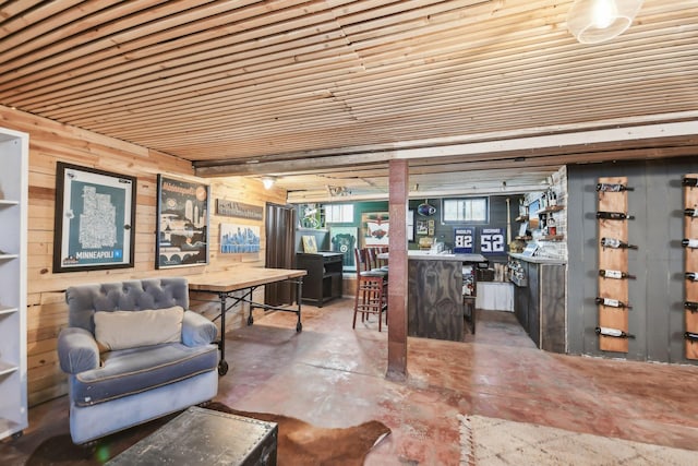 interior space featuring bar area, wooden walls, unfinished concrete flooring, and wooden ceiling
