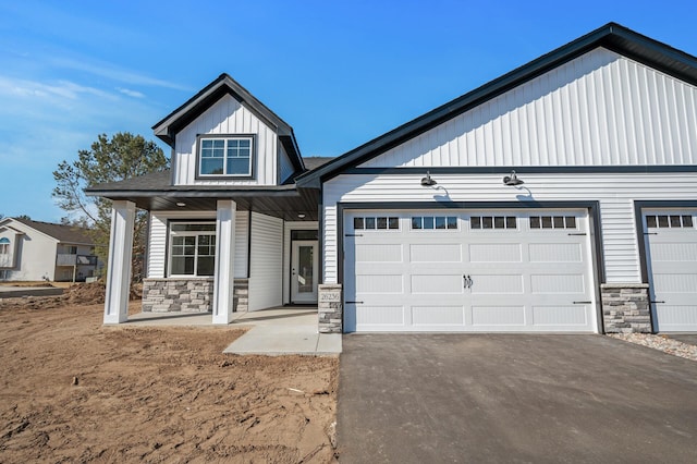 26284 1st St W, Zimmerman, MN 55398 - view of front of property with a porch, an attached garage, stone siding, aphalt driveway, and board and batten siding