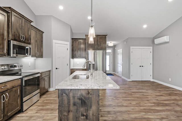 26284 1st St W, Zimmerman, MN 55398 - kitchen with dark brown cabinetry, an AC wall unit, an island with sink, appliances with stainless steel finishes, and a sink
