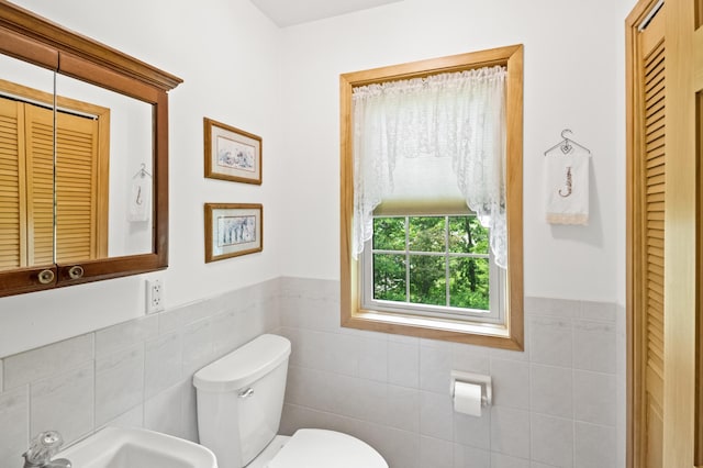 20437 County Highway 65, Henning, MN 56551 - bathroom with tile walls, a closet, toilet, a wainscoted wall, and a sink