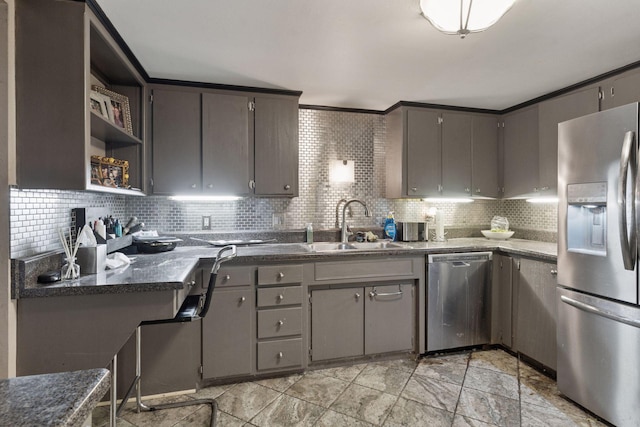 kitchen with appliances with stainless steel finishes, a sink, gray cabinets, and backsplash
