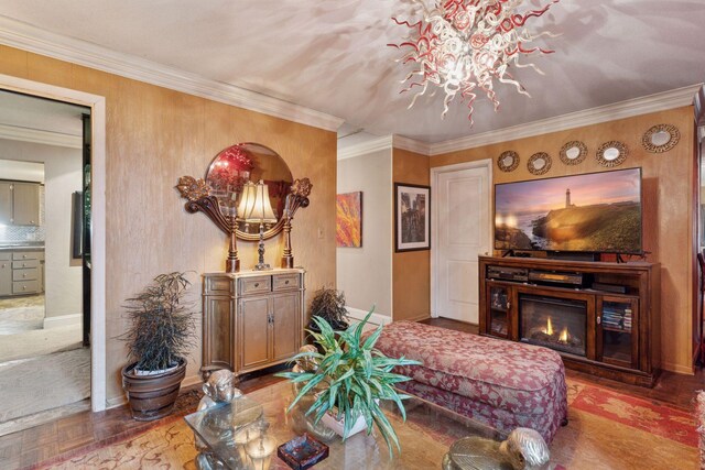 living area with baseboards, crown molding, a chandelier, and a glass covered fireplace