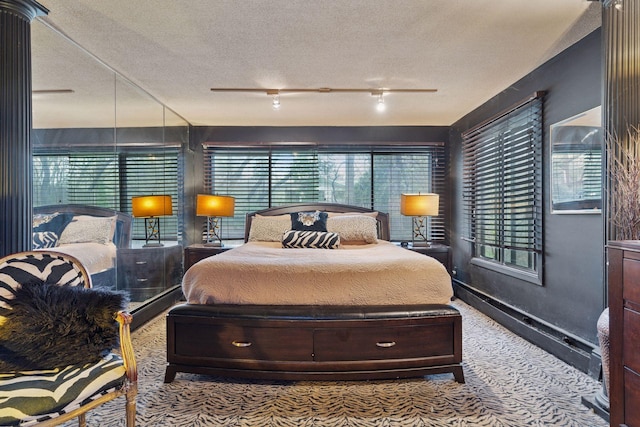 carpeted bedroom with a textured ceiling, rail lighting, and baseboards