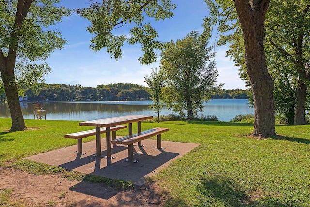 surrounding community with a water view, a lawn, and a wooded view