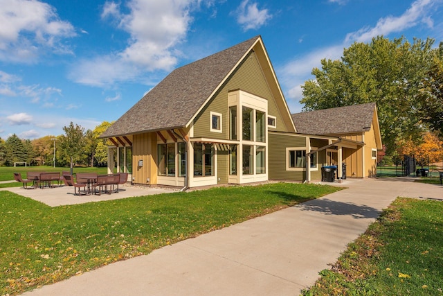 back of house featuring board and batten siding, a yard, a patio, and roof with shingles
