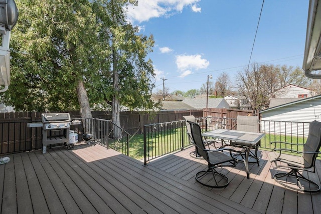 wooden deck featuring a fenced backyard, outdoor dining area, a lawn, and area for grilling