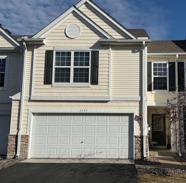 view of front of property with a garage, driveway, and stone siding