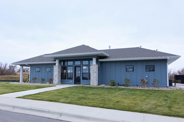 exterior space featuring a lawn, fence, board and batten siding, and roof with shingles