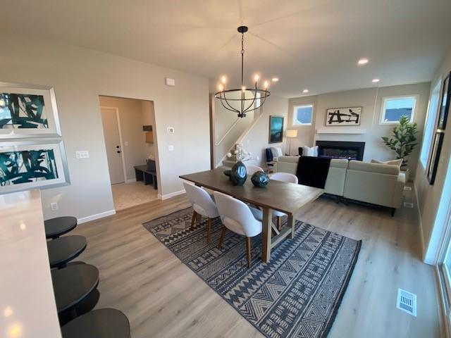 14570 Kingsview Ln N, Dayton, MN 55327 - dining space with light wood finished floors, stairway, a chandelier, a glass covered fireplace, and recessed lighting