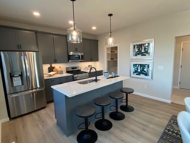 14570 Kingsview Ln N, Dayton, MN 55327 - kitchen with stainless steel appliances, light wood-type flooring, a kitchen bar, light countertops, and decorative light fixtures