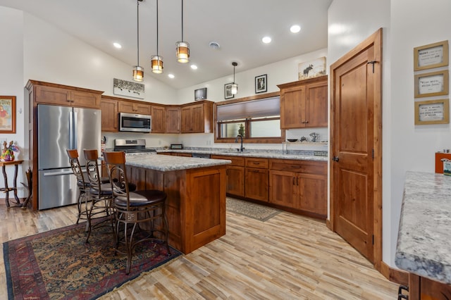 16605 Piper Ln, Brainerd, MN 56401 - kitchen with appliances with stainless steel finishes, a center island, light wood-style flooring, brown cabinets, and pendant lighting