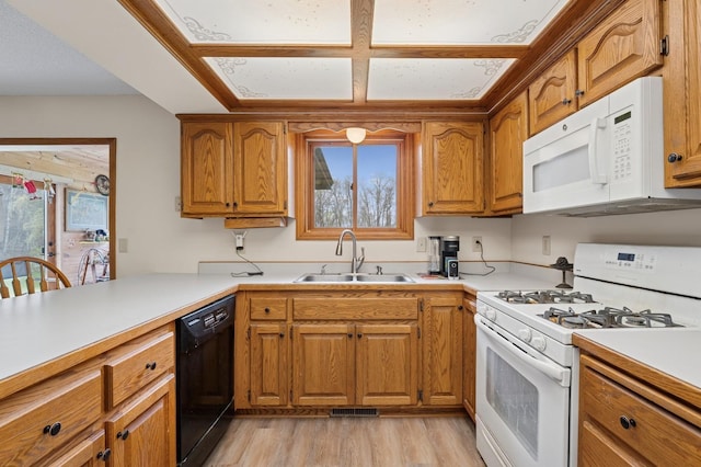 kitchen featuring white appliances, brown cabinetry, and a sink