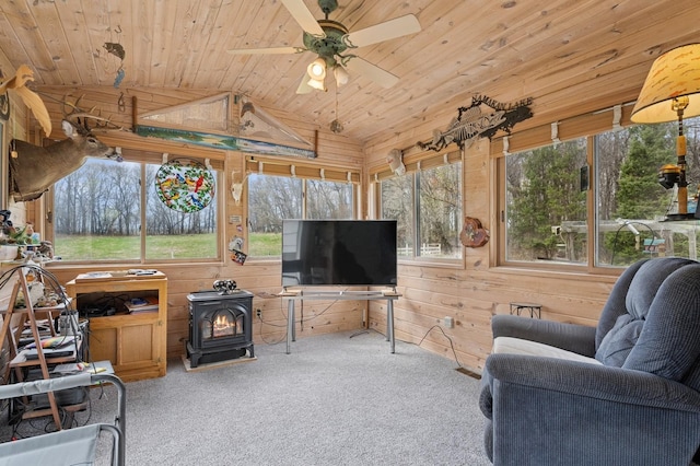 sunroom featuring carpet floors, wood walls, wood ceiling, and a wood stove