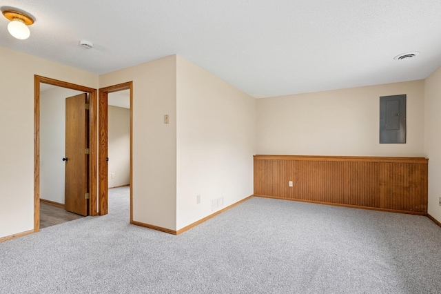 carpeted spare room with baseboards, electric panel, and visible vents