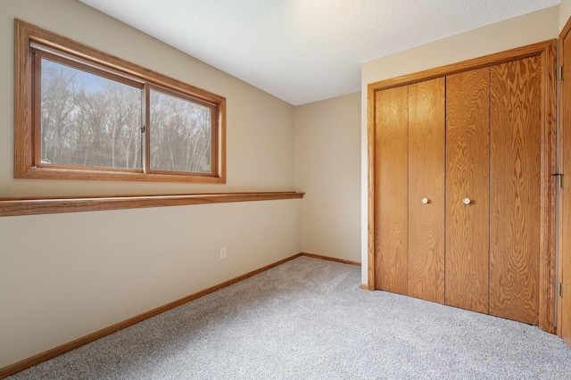 unfurnished bedroom featuring baseboards, carpet, and a closet