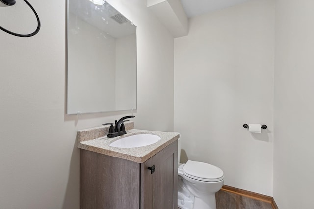 bathroom featuring vanity, visible vents, wood finished floors, toilet, and baseboards