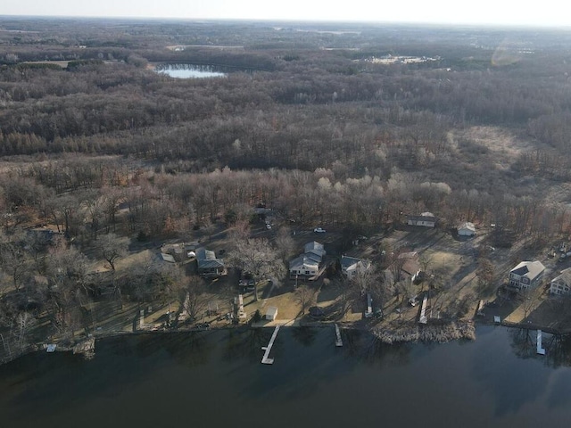 aerial view of property and surrounding area with a large body of water and a heavily wooded area