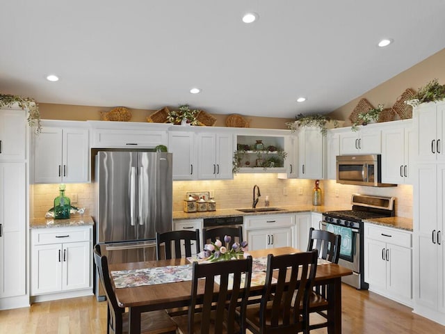 kitchen with appliances with stainless steel finishes, a sink, decorative backsplash, white cabinetry, and recessed lighting