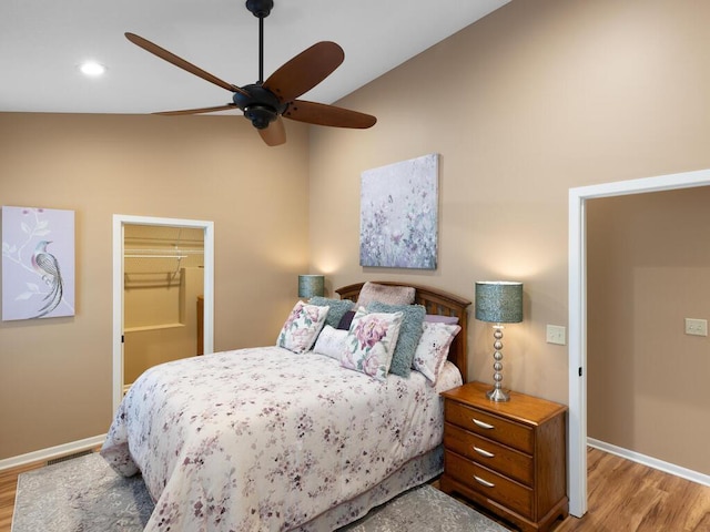 bedroom featuring light wood-type flooring, a walk in closet, baseboards, recessed lighting, and ceiling fan