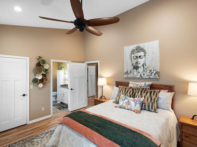 bedroom featuring high vaulted ceiling, wood finished floors, baseboards, connected bathroom, and a ceiling fan