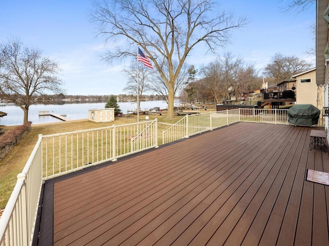 wooden terrace with a water view, a lawn, and grilling area