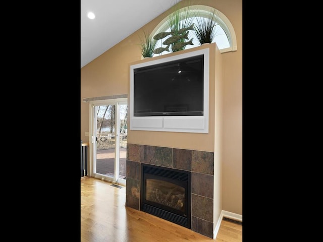 unfurnished living room with wood finished floors, a fireplace, and lofted ceiling