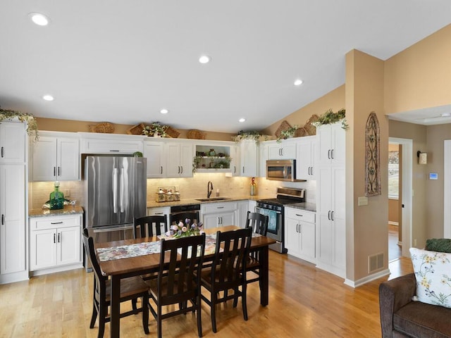 dining space featuring light wood-style floors, recessed lighting, vaulted ceiling, and baseboards