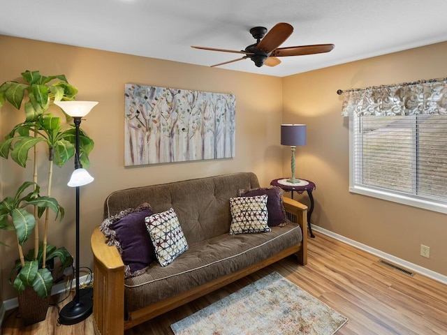 living room featuring baseboards, a ceiling fan, and wood finished floors