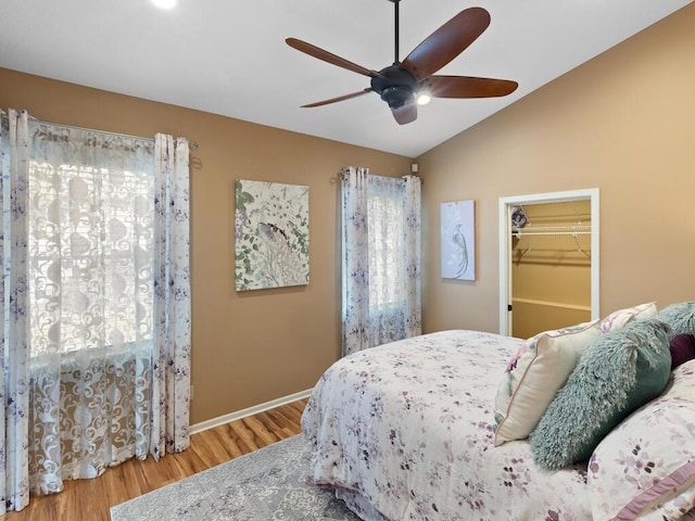 bedroom with wood finished floors, lofted ceiling, a spacious closet, baseboards, and ceiling fan