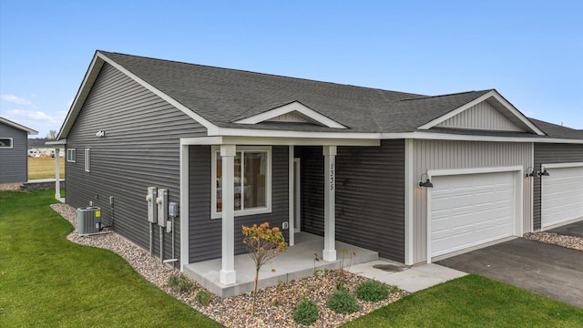 ranch-style house with a garage, a front yard, a shingled roof, and covered porch