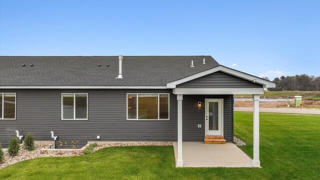 back of property featuring a yard, entry steps, a shingled roof, and a patio area