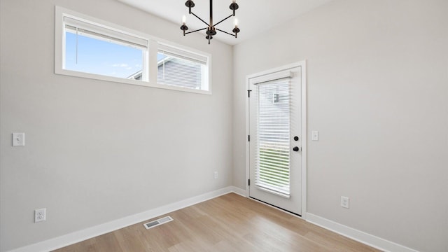 doorway to outside with light wood-style floors, visible vents, baseboards, and an inviting chandelier
