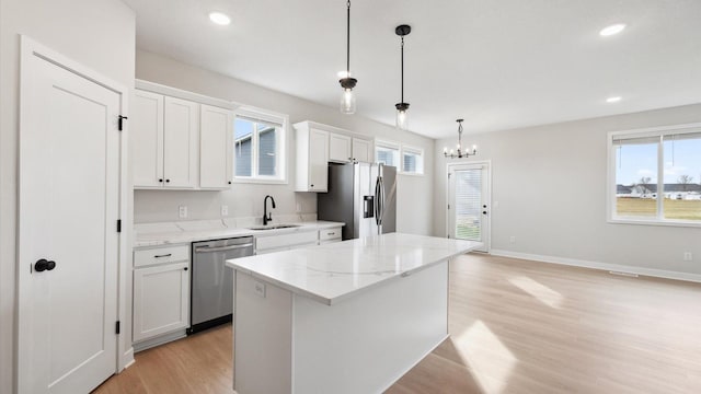 kitchen with light wood-style flooring, a kitchen island, a sink, stainless steel appliances, and plenty of natural light