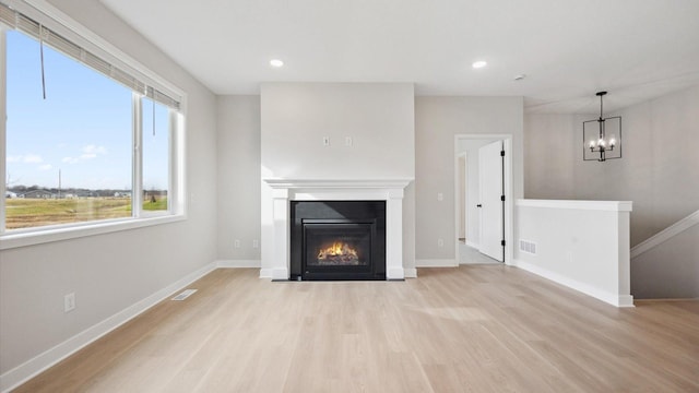 unfurnished living room with visible vents, baseboards, a notable chandelier, recessed lighting, and wood finished floors