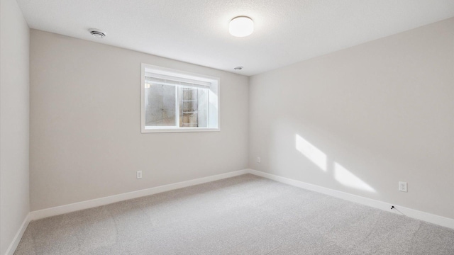 spare room with carpet floors, baseboards, and a textured ceiling