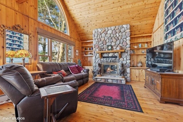 living area with high vaulted ceiling, light wood-type flooring, wood ceiling, wood walls, and built in shelves