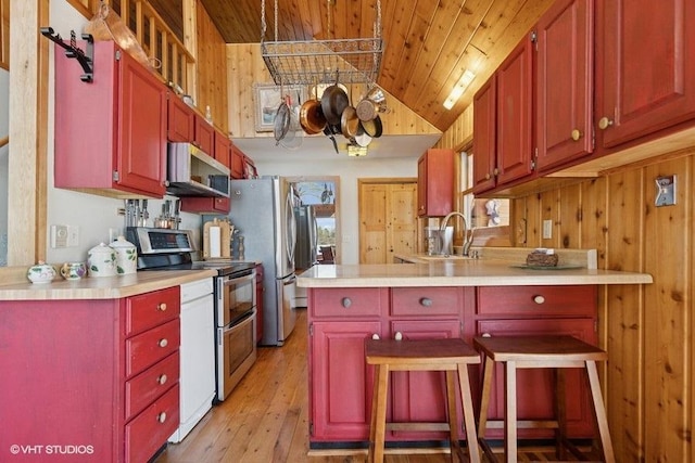 kitchen featuring vaulted ceiling, wooden ceiling, light countertops, a sink, and stainless steel appliances
