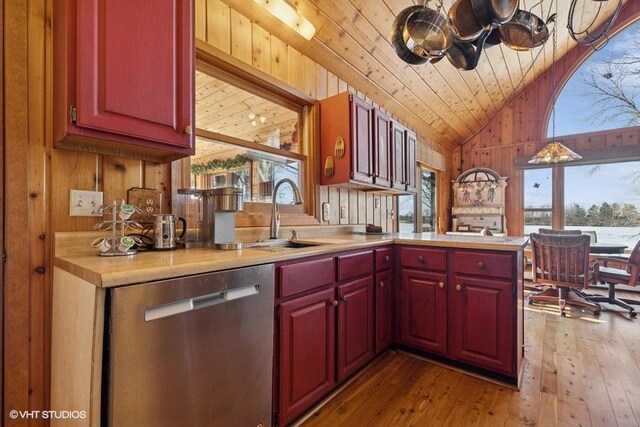 kitchen with wooden walls, a wealth of natural light, vaulted ceiling, and dishwasher