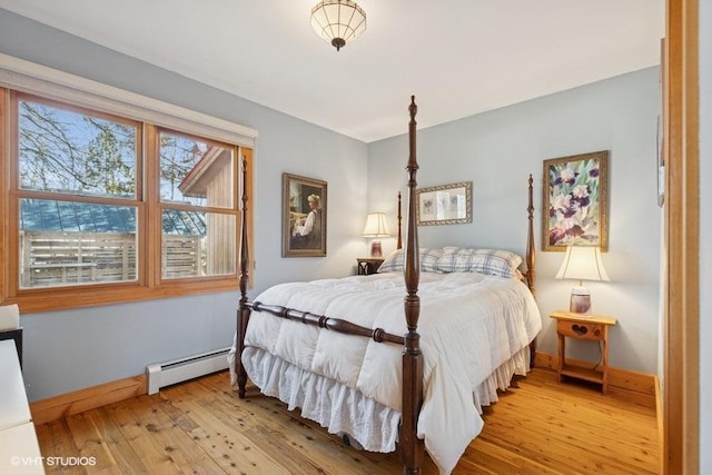 bedroom featuring baseboard heating, light wood-style floors, and baseboards
