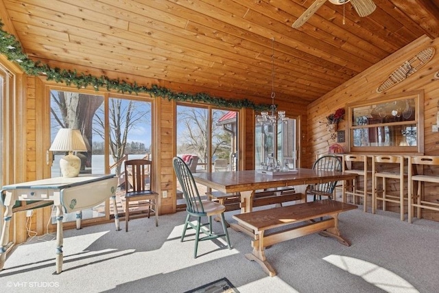 dining room with wood ceiling, ceiling fan with notable chandelier, wood walls, and carpet floors