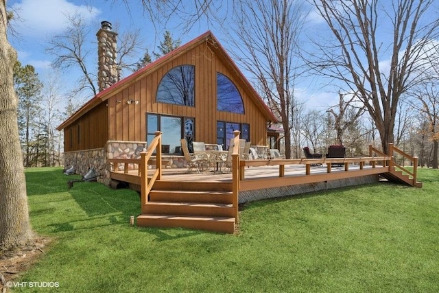 rear view of property featuring a wooden deck, stone siding, and a lawn