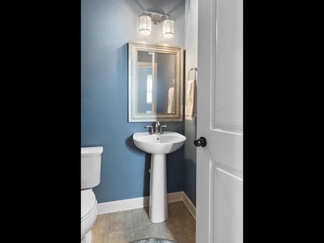 half bath with toilet, tile patterned floors, and baseboards