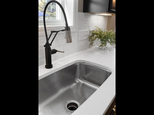 room details featuring tasteful backsplash, a sink, and light stone countertops