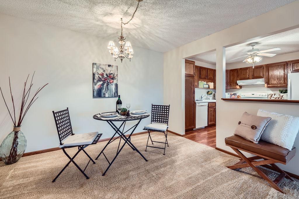 10600 43rd Ave N Unit 205, Plymouth, MN 55442 - dining area featuring ceiling fan with notable chandelier, carpet flooring, and a textured ceiling