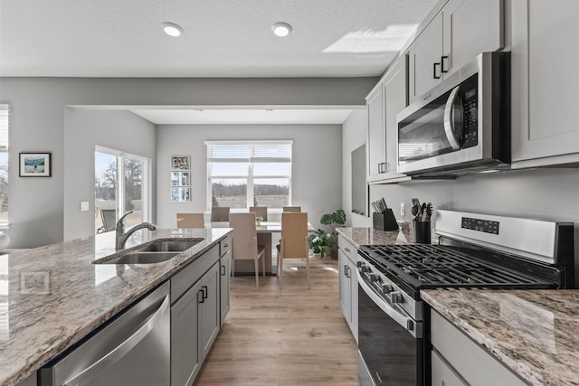 12678 Erskin St NE, Blaine, MN 55449 - kitchen featuring appliances with stainless steel finishes, a sink, light wood-type flooring, light stone countertops, and gray cabinets
