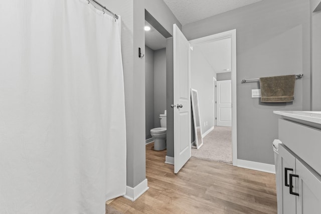12678 Erskin St NE, Blaine, MN 55449 - bathroom with toilet, vanity, wood finished floors, baseboards, and curtained shower